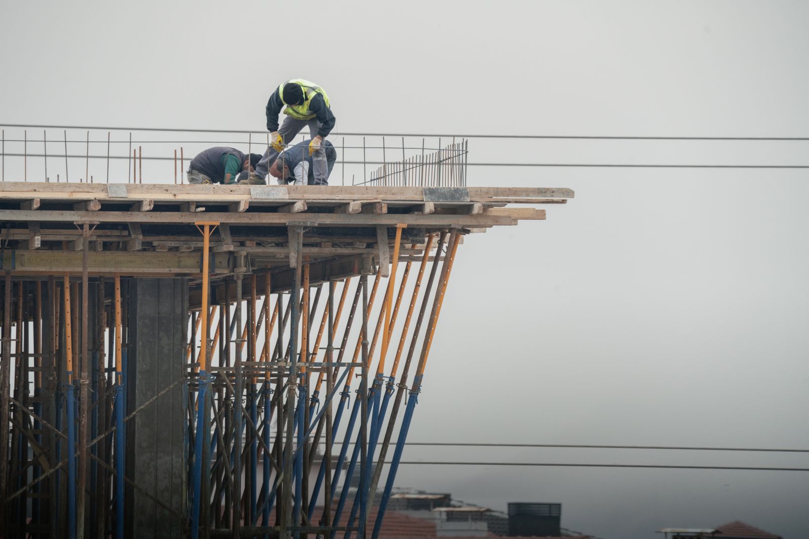 高層ビルの建設現場で複数の職人が協力して作業している